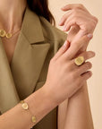 Person wearing gold jewelry on a beige background