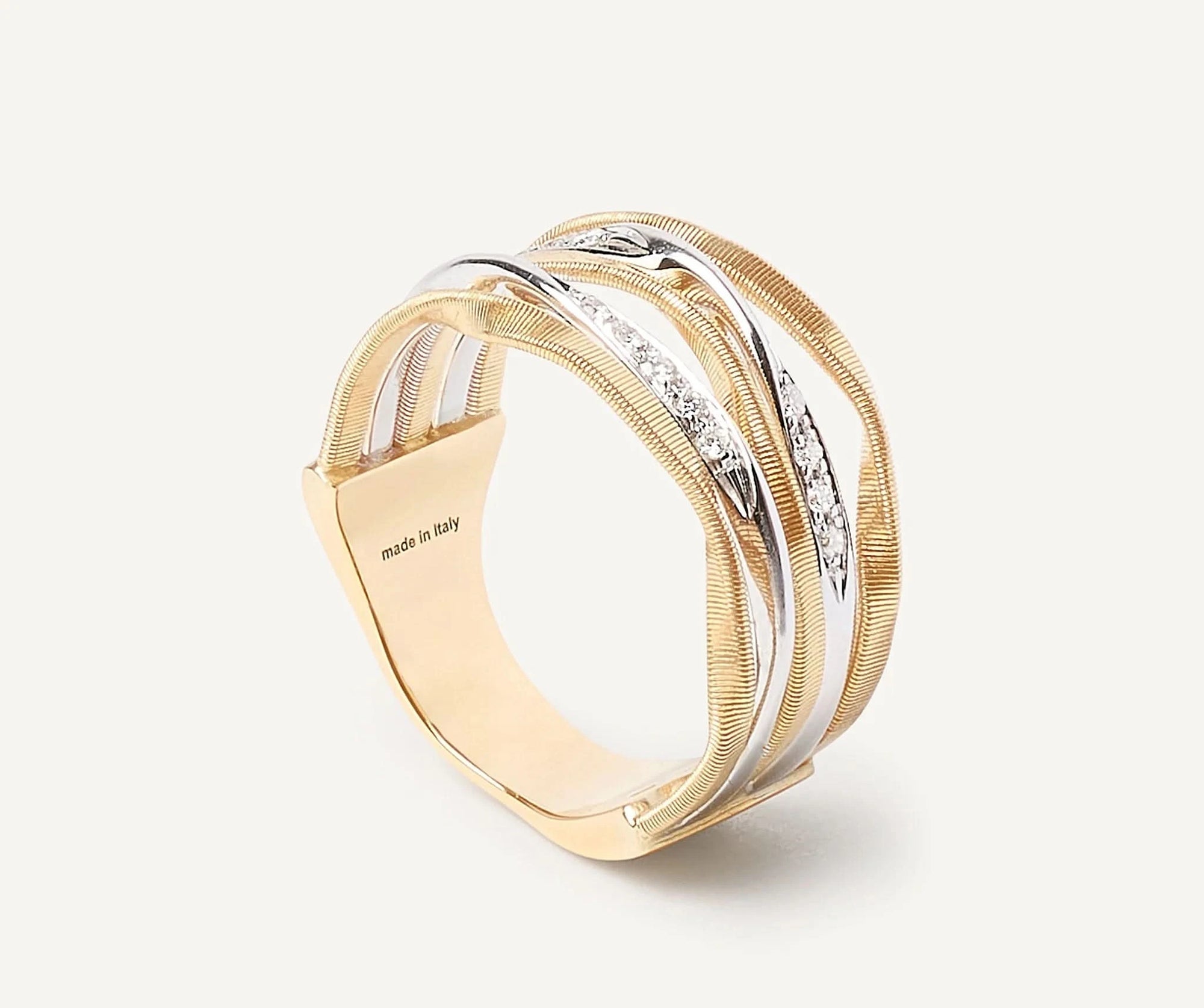 Gold and white gold ring with 'made in Italy' engraving on a white background side view
