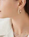 Close-up of a person wearing gold hoop earrings with a white background