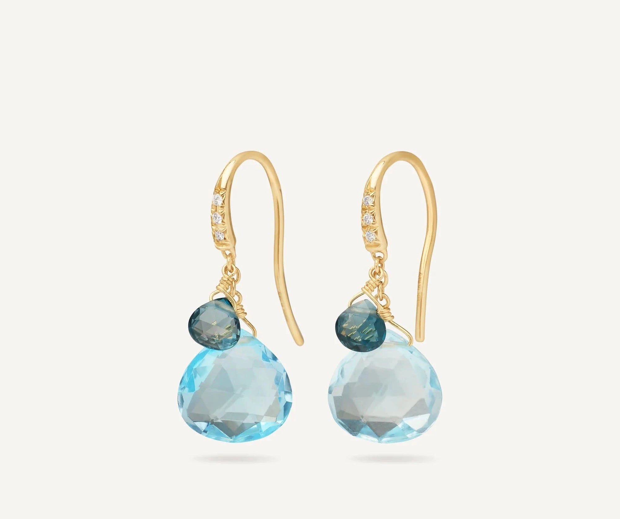 Gold earrings with blue gemstones on a white background