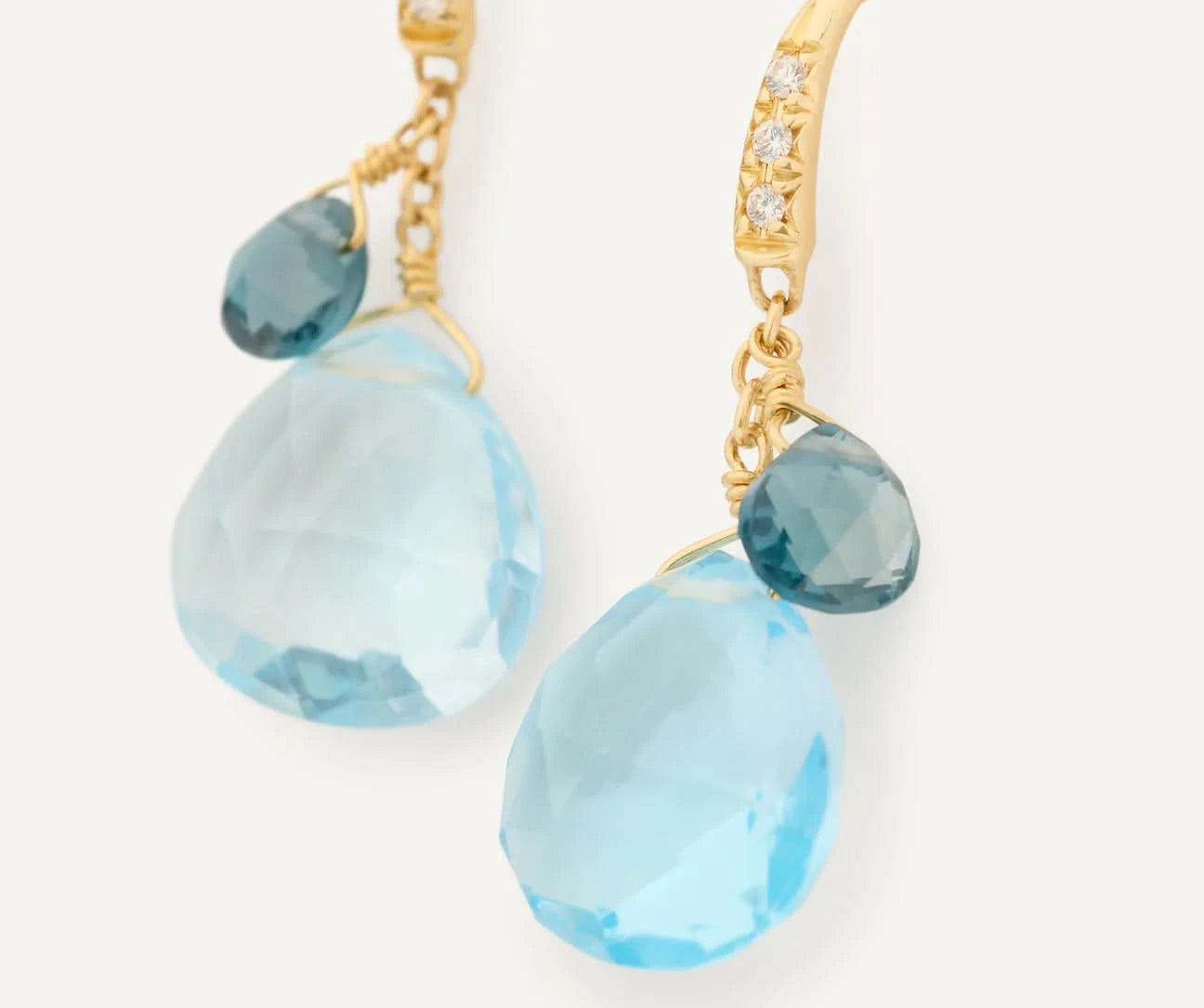 Gold earrings with blue teardrop-shaped gemstones on a white background