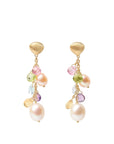 A pair of gold dangle earrings featuring a textured gold top, small multicolored faceted gemstones, and large white freshwater pearls hanging from gold chains, set against a light off-white background.
