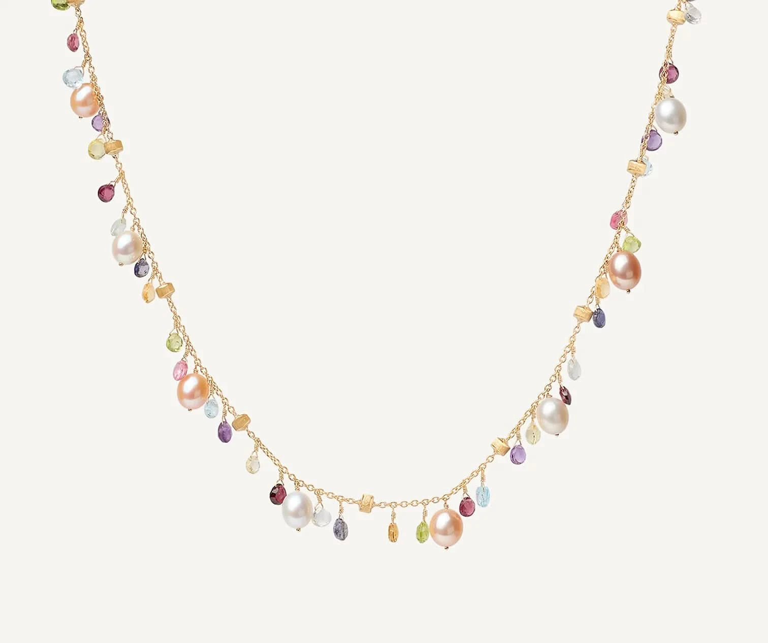 A delicate gold chain necklace featuring a series of dangling charms, including large iridescent baroque pearls, small teardrop gemstones in pink, purple, green, and blue, and tiny gold beads, set against a solid off-white background.