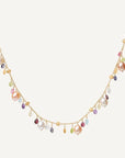A delicate gold chain necklace featuring a series of dangling charms, including large iridescent baroque pearls, small teardrop gemstones in pink, purple, green, and blue, and tiny gold beads, set against a solid off-white background.