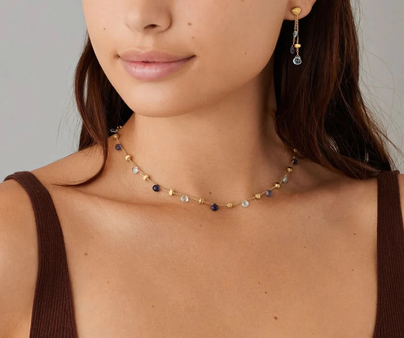 Woman wearing a delicate necklace with small beads on a neutral background