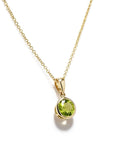 Side view of 14K yellow gold 1.46ct round peridot bezel pendant with polished bail; chain not included