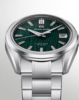 A Grand Seiko stainless steel watch with a textured dark green dial, silver-tone case, and matching metal link bracelet, shown on a light gray gradient background.