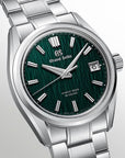 A Grand Seiko wristwatch with a polished silver-tone stainless steel case and bracelet, featuring a textured dark green dial with silver-tone indices and a date window.