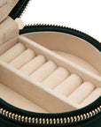 Round jewelry case with beige interior and gold zipper on a white background