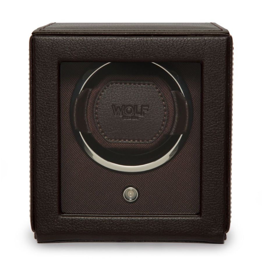 A dark brown leather-wrapped watch winder box with a clear front window showing a single watch winding carousel inside. The center features a circular leather patch with the embossed brand name 'WOLF'.