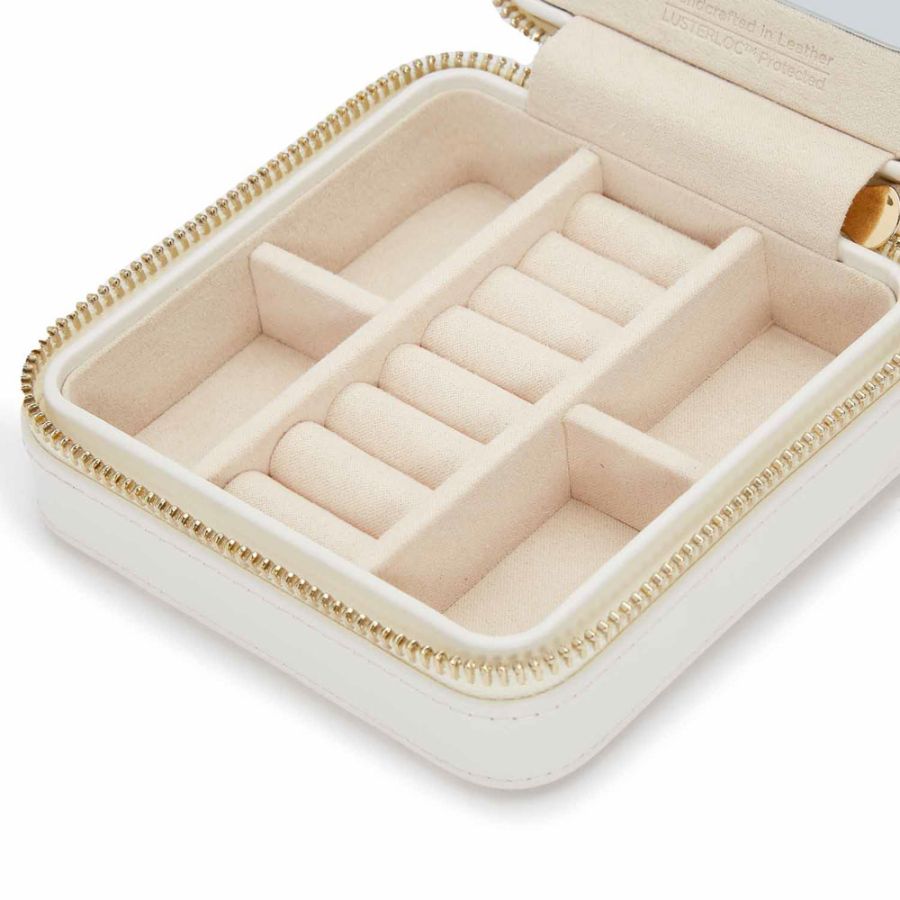 Beige jewelry box inside with gold tone zipper on a white background