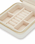 Beige jewelry box inside with gold tone zipper on a white background