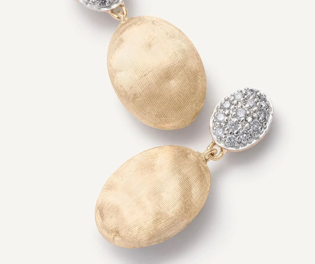 A pair of gold drop earrings with large textured oval dangles and round pavé-set clear stones, photographed on a clean white background.
