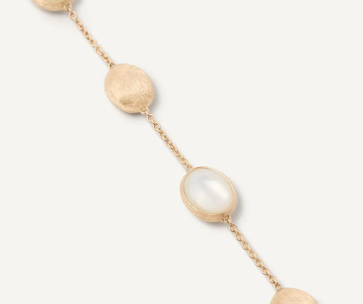 Gold bracelet with mother of pearl beads on a white background close up