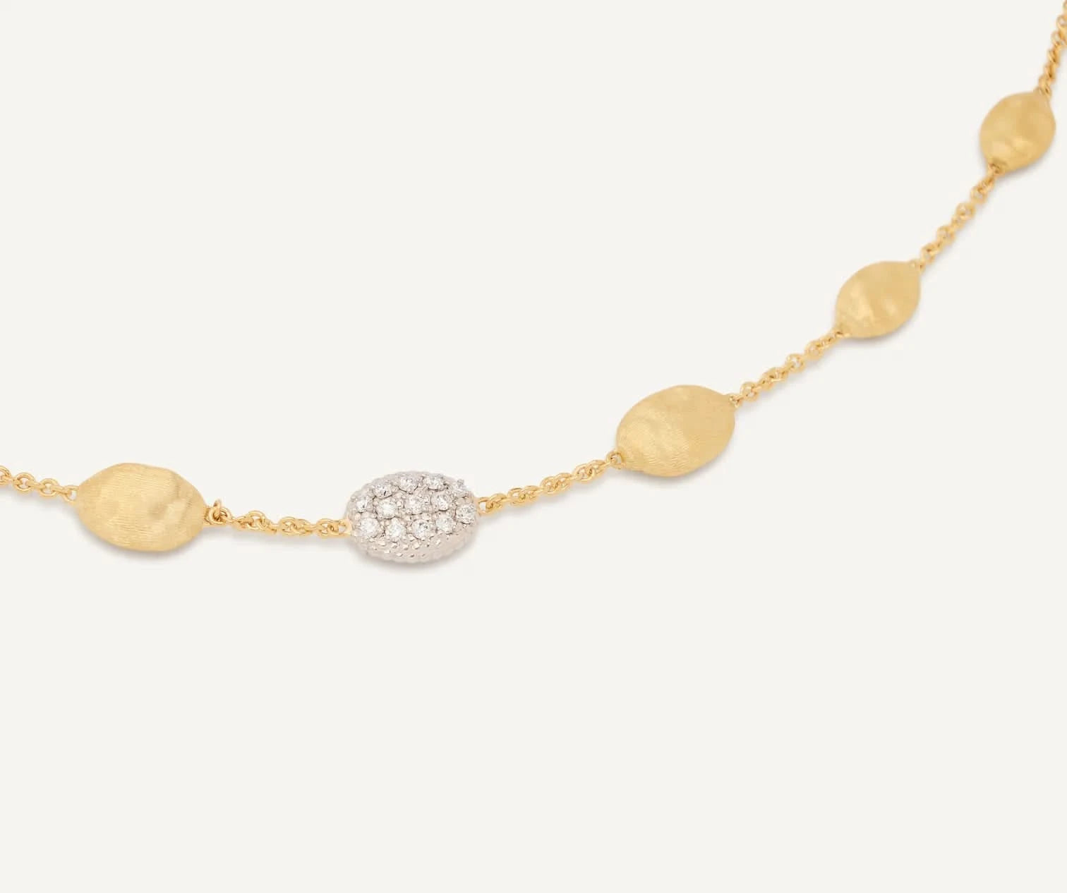 Gold necklace with round and oval beads on a white background