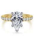 Gold ring with a pear-shaped diamond on a white background
