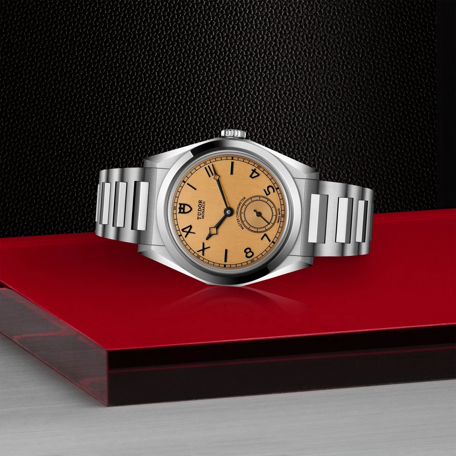 Silver watch with a brown face on a red platform against a black background