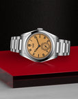 Silver watch with a brown face on a red platform against a black background