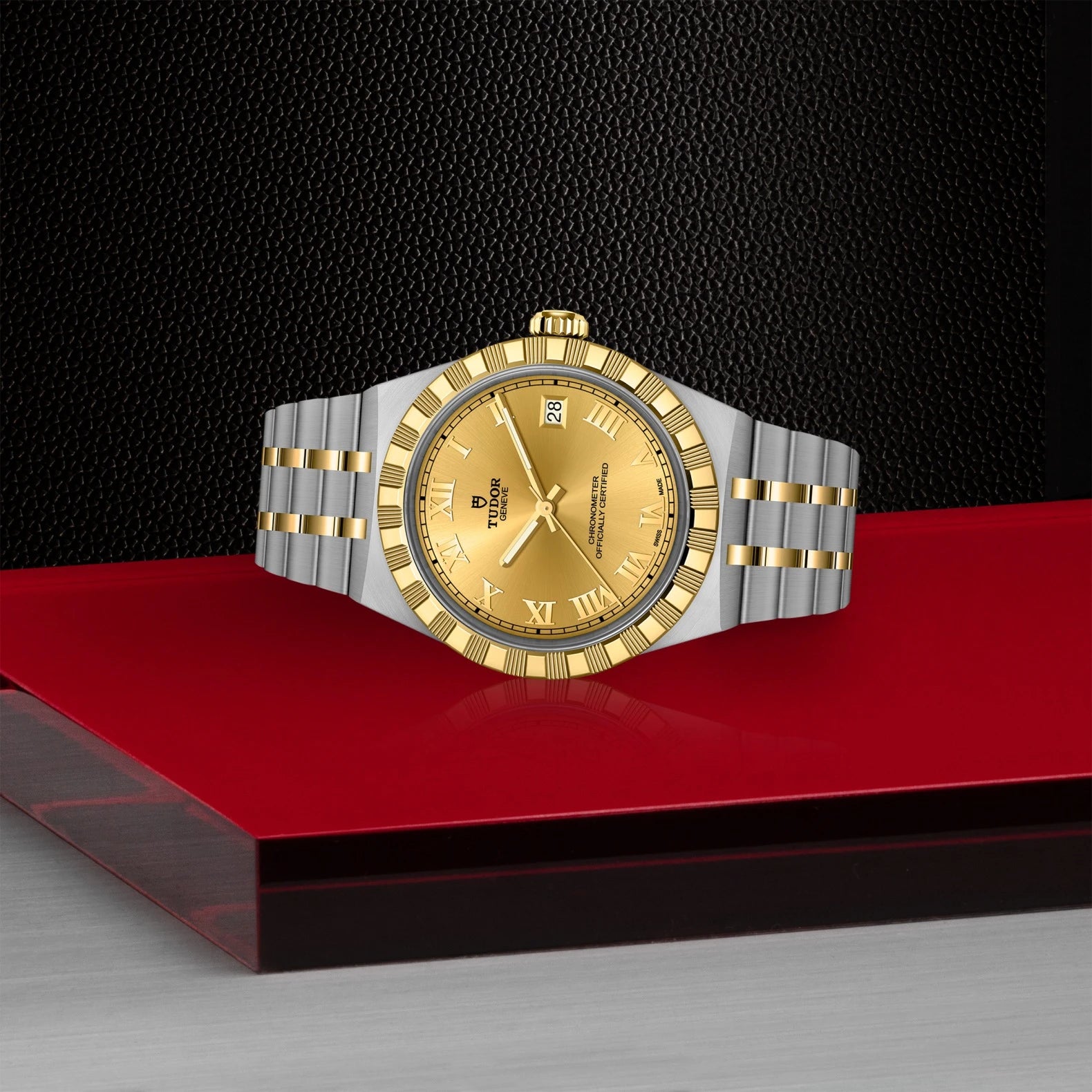 Gold and silver watch on a red platform with a black background