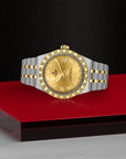 Gold and silver watch on a red platform with a black background