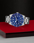 Silver watch with blue face on a red platform against a black background