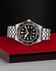 Silver watch with black dial on a red platform against a dark background