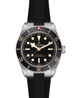 Tudor watch with open black strap and black dial on a white background