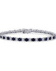 An 18k white gold tennis-style bracelet showcasing an alternating pattern of round blue sapphires and round brilliant diamonds in a shared prong setting, displayed horizontally on a white background
