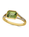 yellow gold ring with a green bezel center and embedded diamonds tilted view  on a white background 