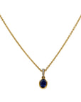 yellow pendant and chain with blue center stone and diamond accents on a white background